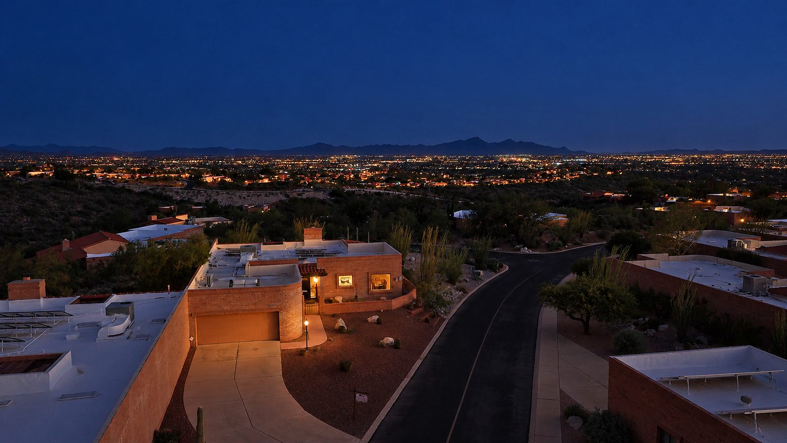 Night photo of a Tucson home with city lights and mountains behind